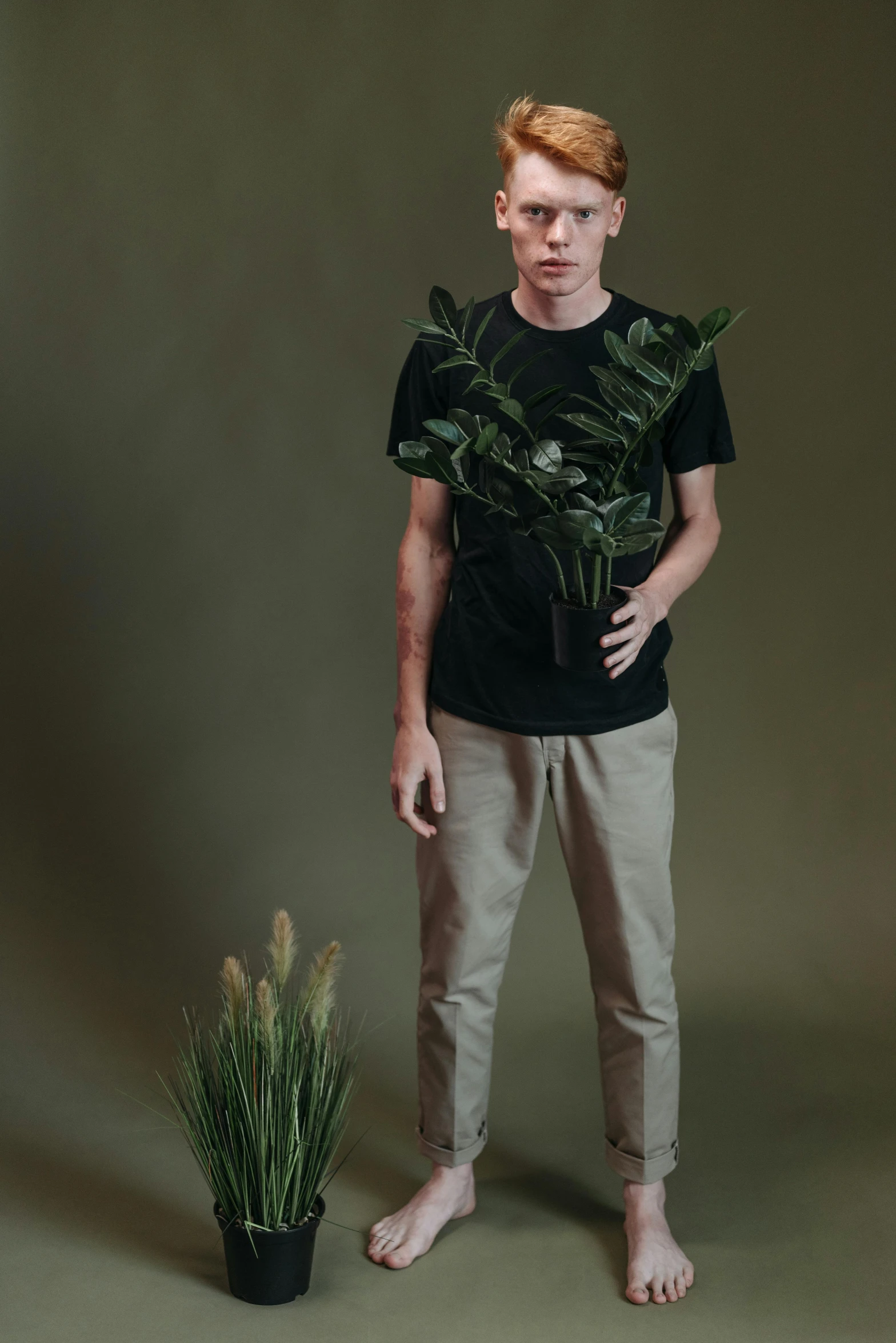 a man standing next to a potted plant, trending on unsplash, fullbody portrait, tommy 1 6 years old, studio photo, greens)