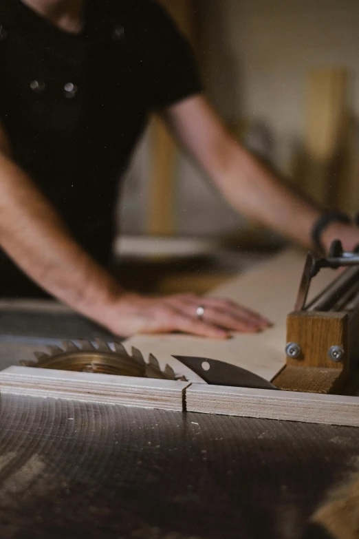 a person using a table saw to cut a piece of wood, by David Simpson, trending on pexels, process art, looking off to the side, banner, bespoke, wooden trim