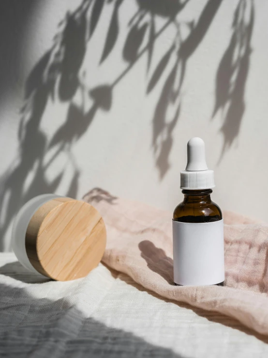 a bottle of essential oil next to a wooden container, unsplash, product view, blank, skincare, experimental studio light