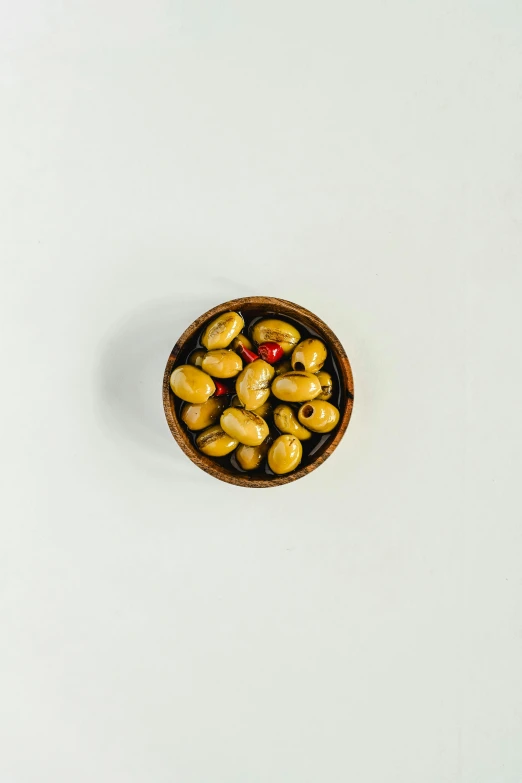 a wooden bowl filled with olives on top of a white table, inspired by Ceferí Olivé, unsplash, miniature product photo, buzzed sides, without background, potato