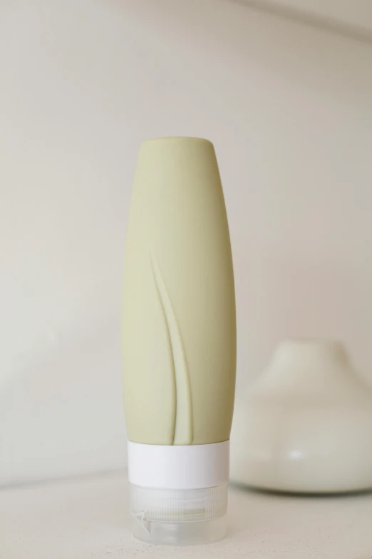 a bottle sitting on top of a counter next to a toothbrush, an abstract sculpture, inspired by Kay Sage, soft green lighting, olive thigh skin, front profile shot, silicone cover