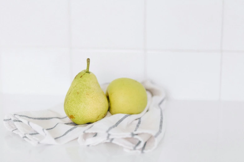 a couple of pears sitting on top of a towel, by Mardi Barrie, unsplash, in the kitchen, white backround, background image