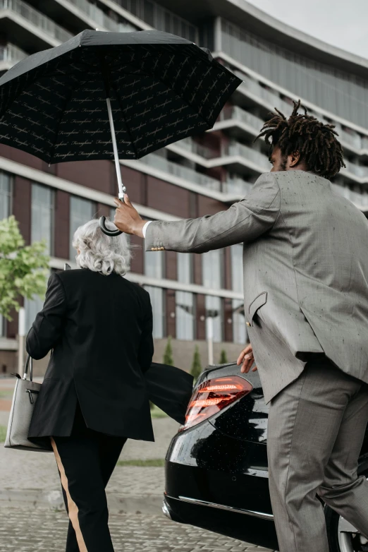 a man standing next to a woman holding an umbrella, pexels contest winner, wearing black grey suit, leaving for battle, young thug, thumbnail