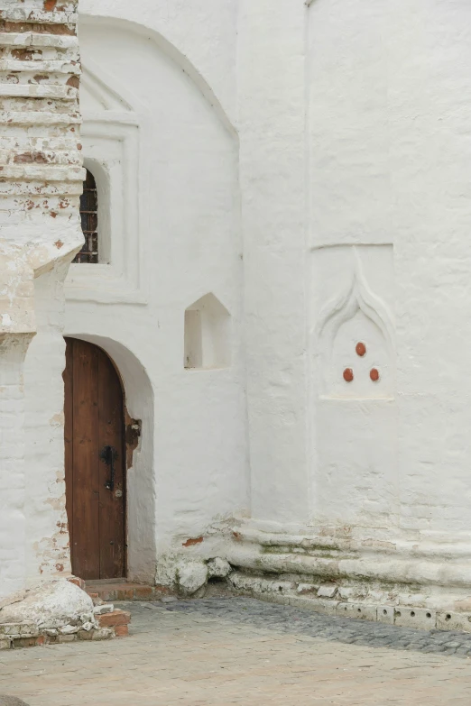 a motorcycle parked in front of a white building, inspired by Andrei Rublev, unsplash, romanesque, door, indian temple, white paint, crypt