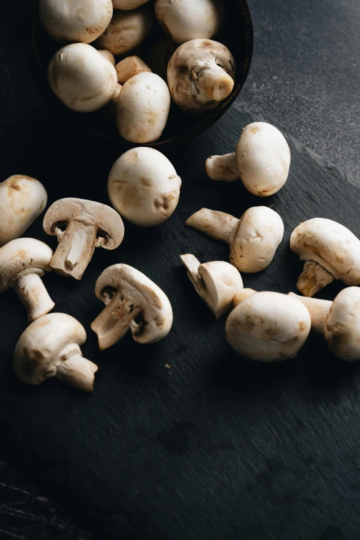 a bowl filled with mushrooms sitting on top of a table, on a black background, in rows, whites, 2 1 0 mm