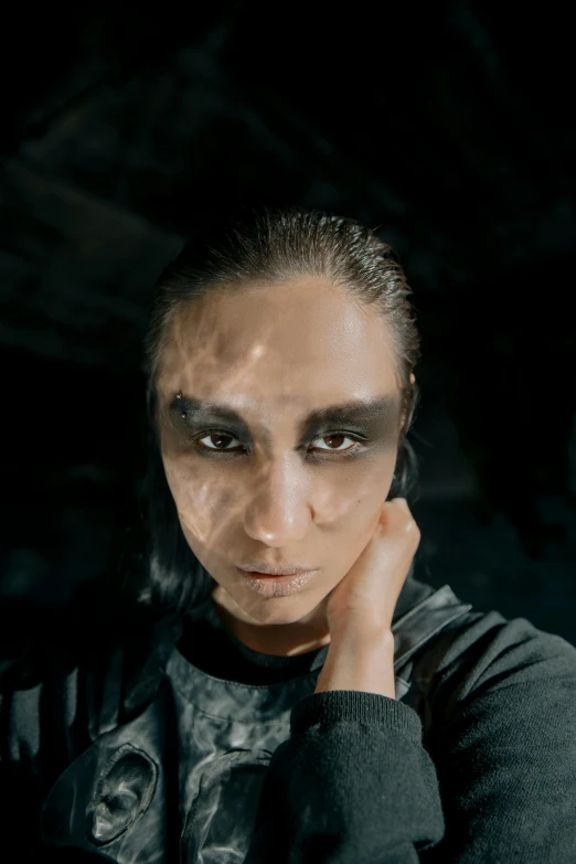 a close up of a person with makeup on, an album cover, inspired by Ignacy Witkiewicz, antipodeans, androgyny, hybrid of gal gadot, in a black room, portrait of bedouin d&d