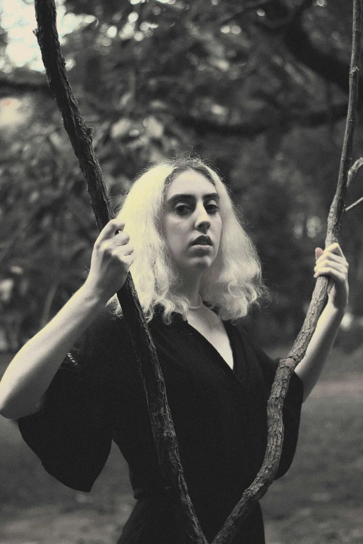 a black and white photo of a woman holding a tree branch, a black and white photo, by Jessie Alexandra Dick, albino hair, promo image, asher duran, pitchfork