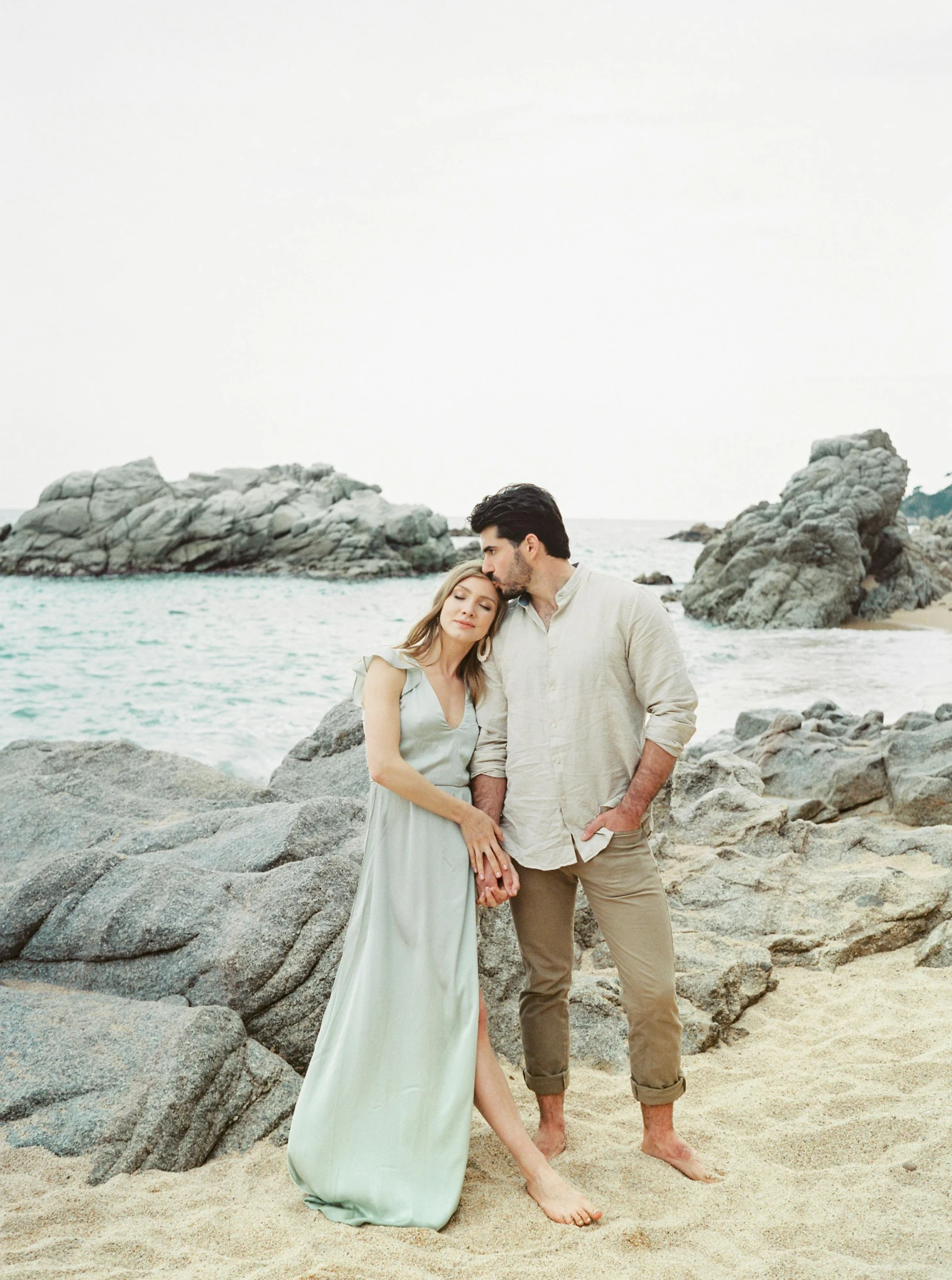 a man and woman standing next to each other on a beach, a picture, flowy hair standing on a rock, light grey backdrop, greece, instagram photo