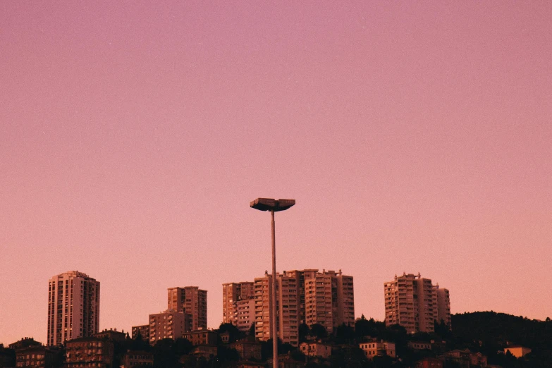 a man flying a kite on top of a lush green field, inspired by Elsa Bleda, pexels contest winner, brutalism, dystopian city skyline at night, pink concrete, istanbul, 33mm photo