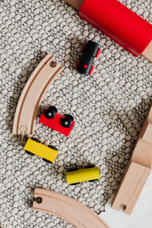 a wooden train set sitting on top of a carpet, a cartoon, trending on unsplash, flat lay, solid colours material, developers, detail shot