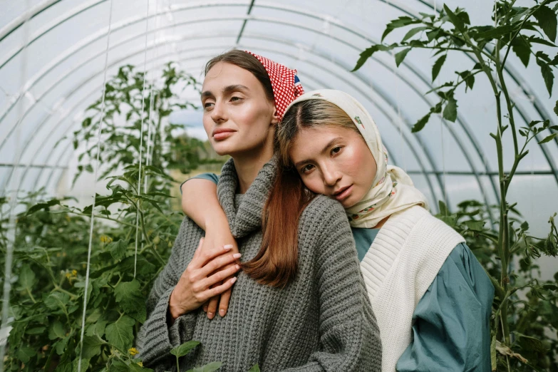 two women standing next to each other in a greenhouse, by Julia Pishtar, trending on pexels, renaissance, scarf, attractive girl, hijab, wearing a sweater