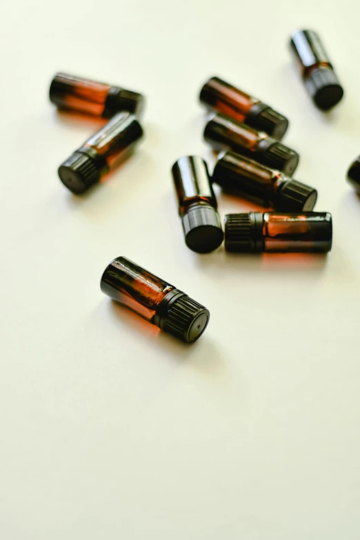 several bottles of essential oils on a white surface, a picture, by Alison Watt, pexels, brown:-2, low - angle shot from behind, miniatures, 1 6 x 1 6