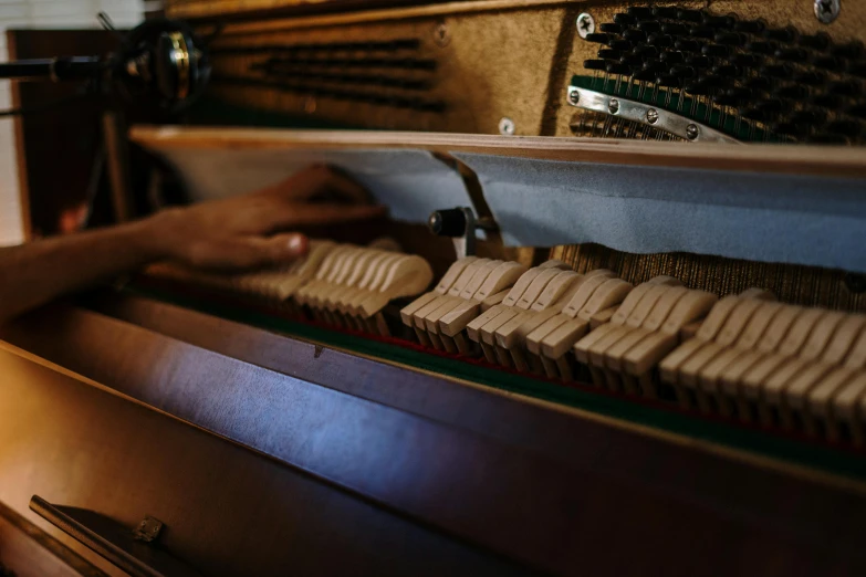 a close up of a person playing a piano, in a workshop, in a row, brown, with everything in its place