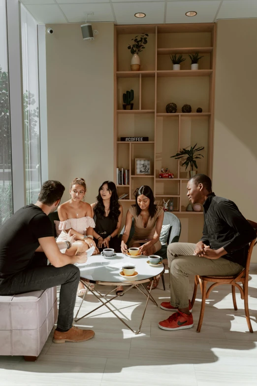 a group of people sitting around a table, on a coffee table, singapore, sol retreat, multiple stories