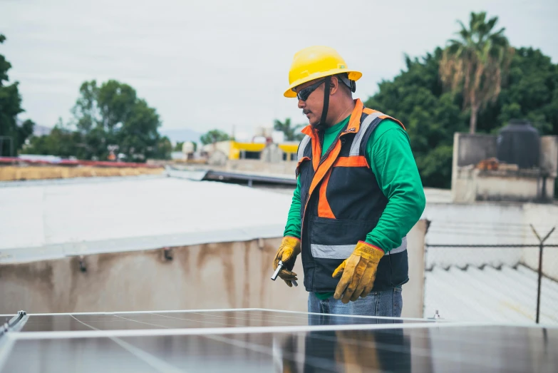 a man standing on top of a roof next to a solar panel, worksafe. instagram photo, getty images, mechanic, a green