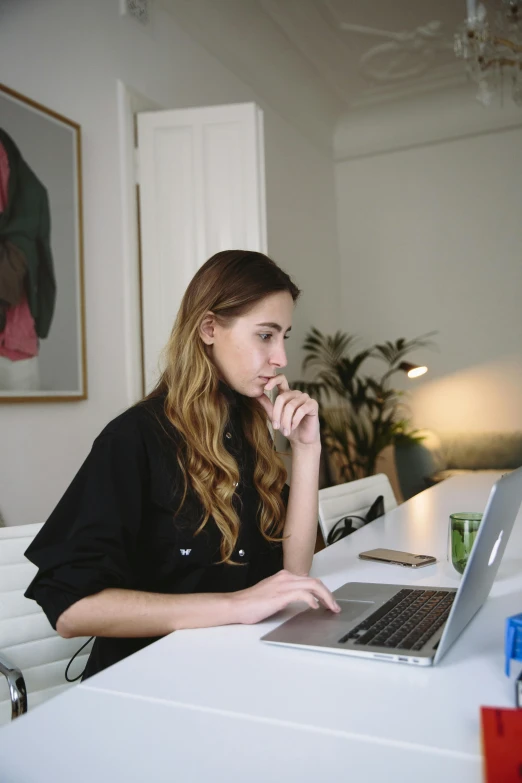 a woman sitting in front of a laptop computer, by Carey Morris, pexels contest winner, on a white table, concentrated look, jen atkin, reddit post