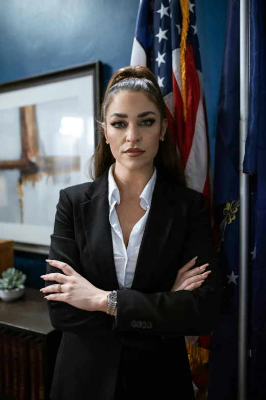 a woman standing in front of an american flag, in a strict suit, kailee mandel, in an office, intense expression