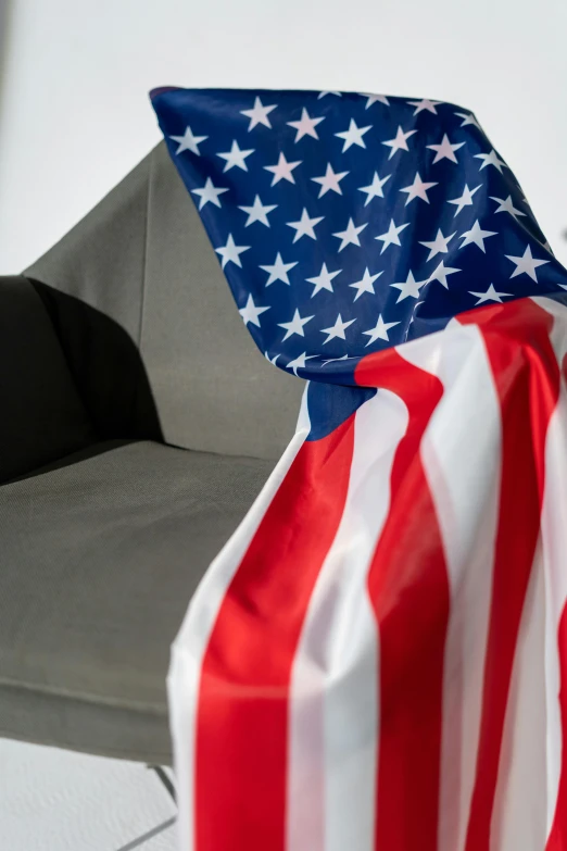 a chair with an american flag draped over it, a portrait, unsplash, dynamic closeup, high quality upload, couch, multiple stories