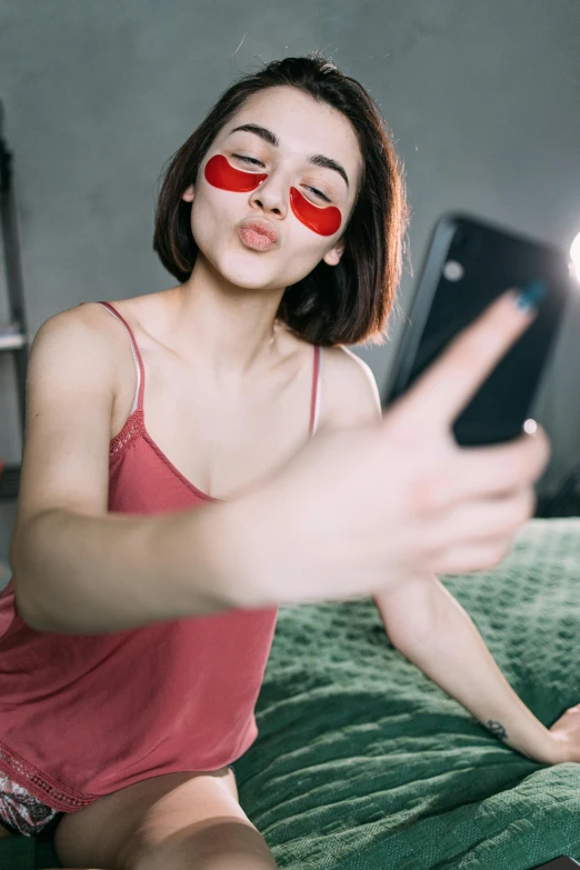 a woman sitting on a bed taking a selfie, trending on pexels, pop art, red contact lenses, kiko mizuhara, digital sunglasses, good lighted photo