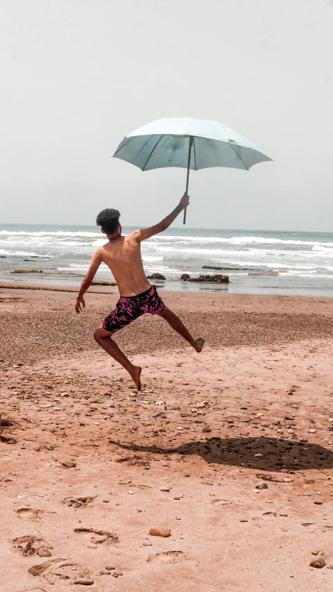 a man running on a beach holding an umbrella, pexels contest winner, arabesque, an olive skinned, t pose, moroccan, thumbnail