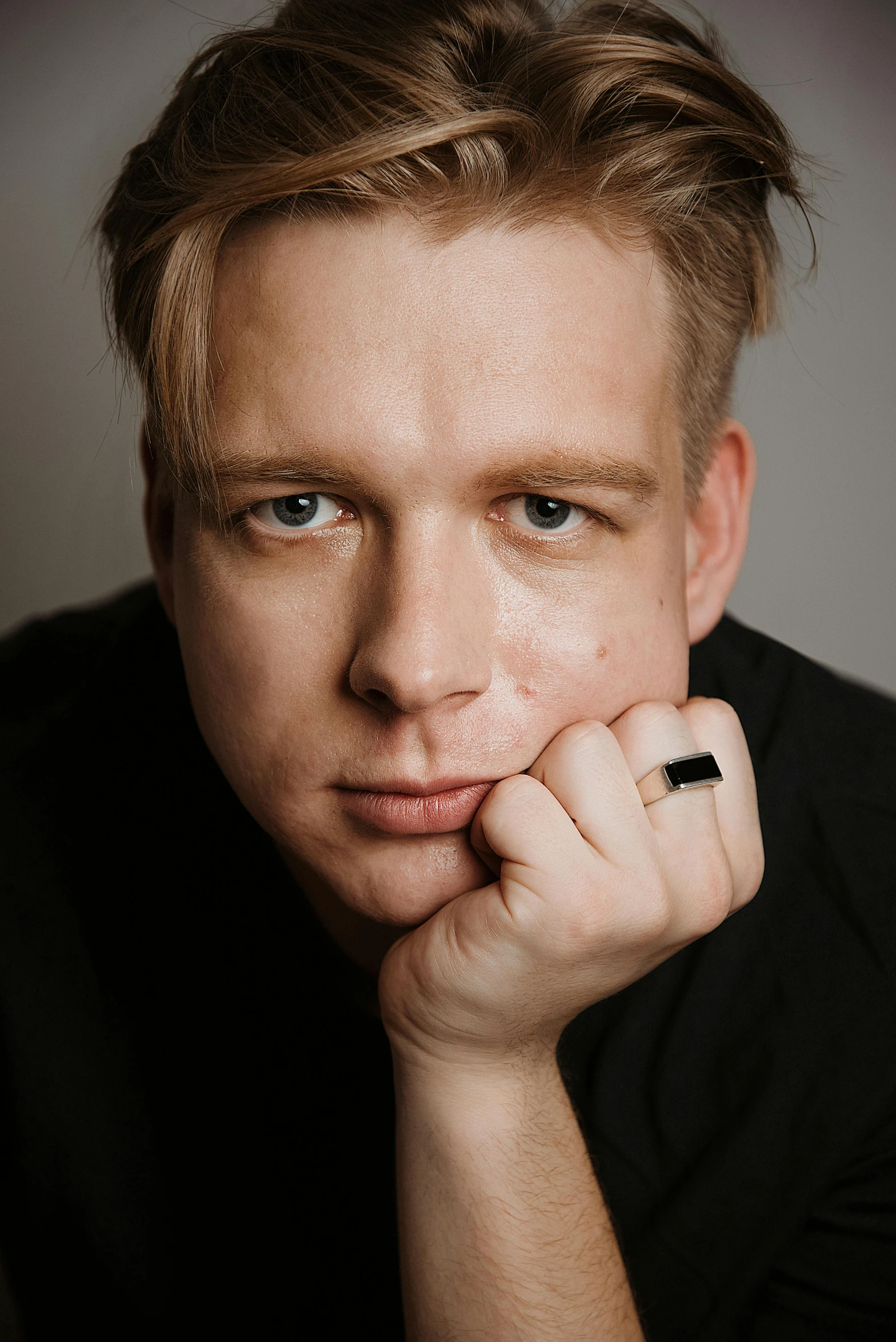 a man in a black shirt posing for a picture, an album cover, inspired by Oskar Lüthy, hand on his cheek, one man is blond, headshot profile picture, anton fadeev 8 k