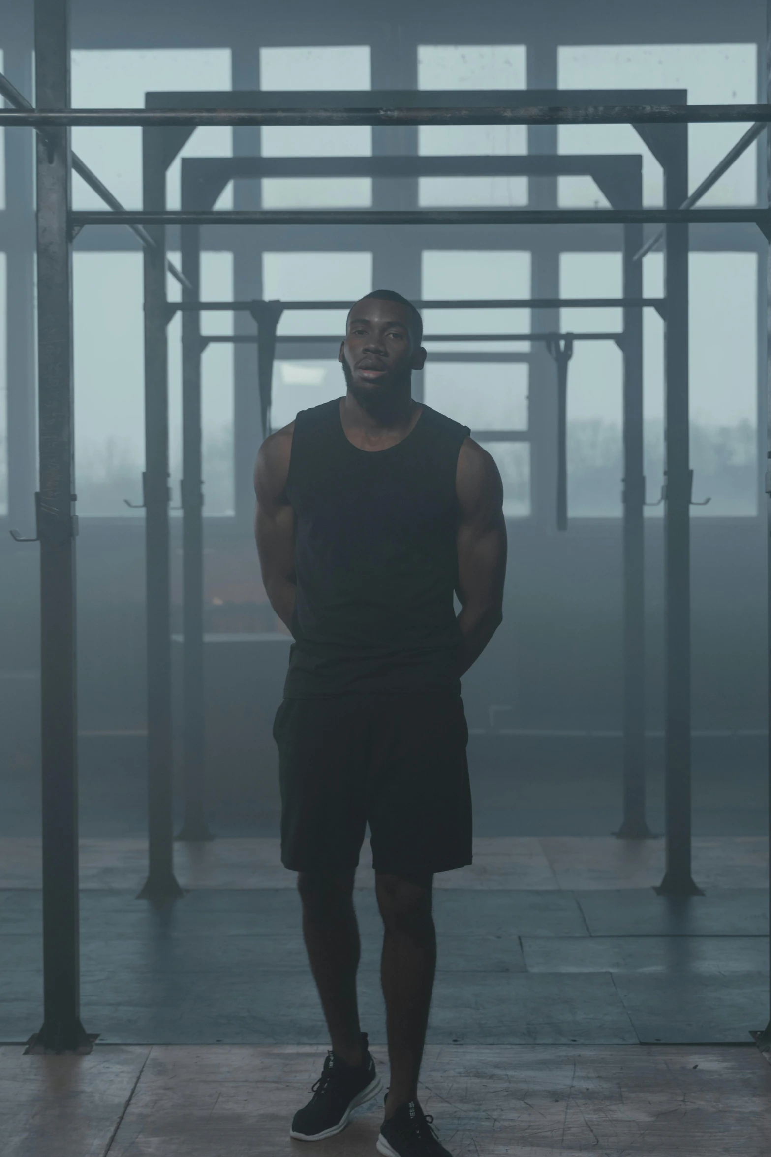 a man standing in front of a metal structure, an album cover, inspired by Terrell James, pexels contest winner, realism, in a gym, still from a music video, mkbhd, (mist)