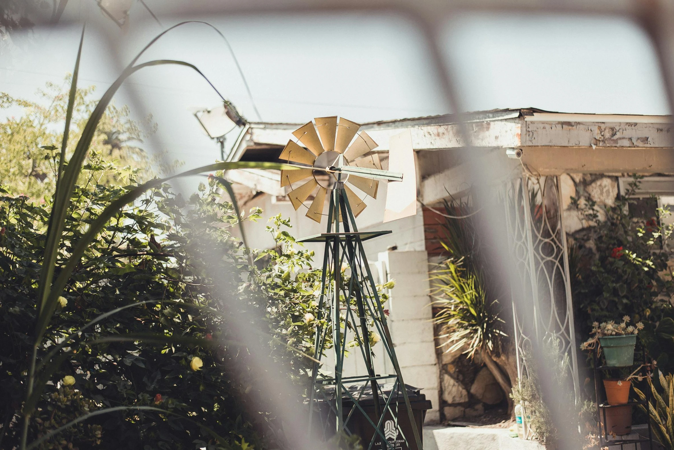 a windmill sitting on top of a lush green field, a portrait, pexels contest winner, kinetic art, in a garden of a house, watering can, southern california, faded and dusty