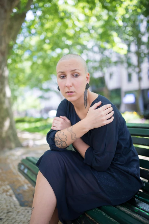 a woman with shaved hair sitting on a bench, square, ptsd, hila klein, 30 years old woman