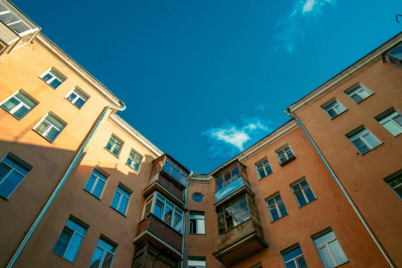 a very tall building with lots of windows, by Tobias Stimmer, unsplash, bauhaus, saint petersburg, tenement buildings, light blue clear sky, post - soviet courtyard