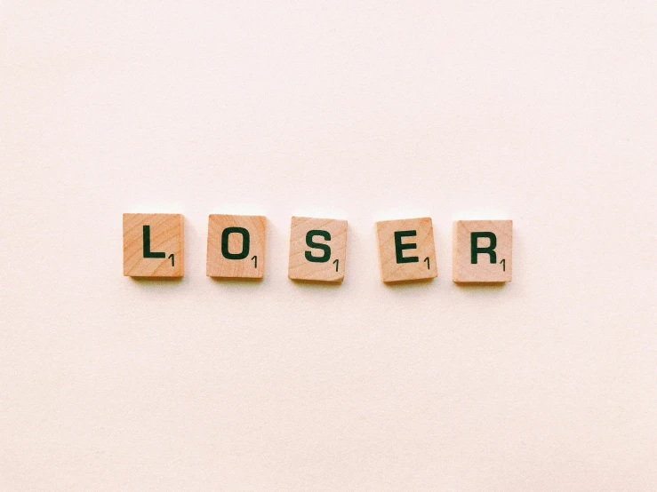 the word loser spelled in scrabbles on a white surface, pexels, letterism, 🦩🪐🐞👩🏻🦳, laser, lost series, tan