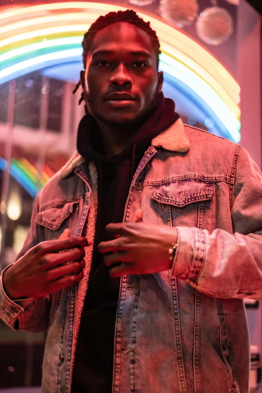 a man standing in front of a neon sign, an album cover, by Amos Ferguson, trending on pexels, realism, jean jacket, young thug, ( ( dark skin ) ), modeled