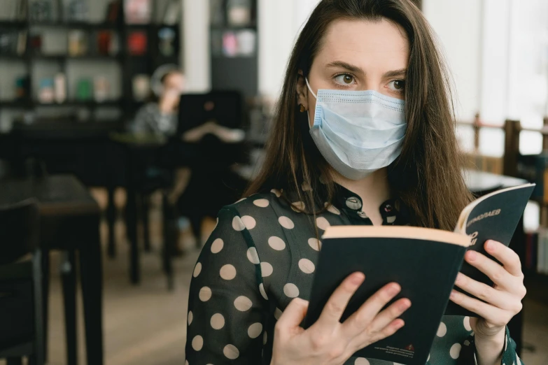 a woman wearing a face mask reading a book, a portrait, trending on pexels, posing in disguise among humans, schools, avatar image, thumbnail