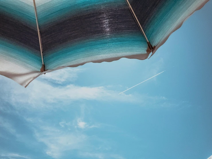 an umbrella with a blue sky in the background, pexels contest winner, light and space, aerial iridecent veins, awnings, holiday season, conde nast traveler photo