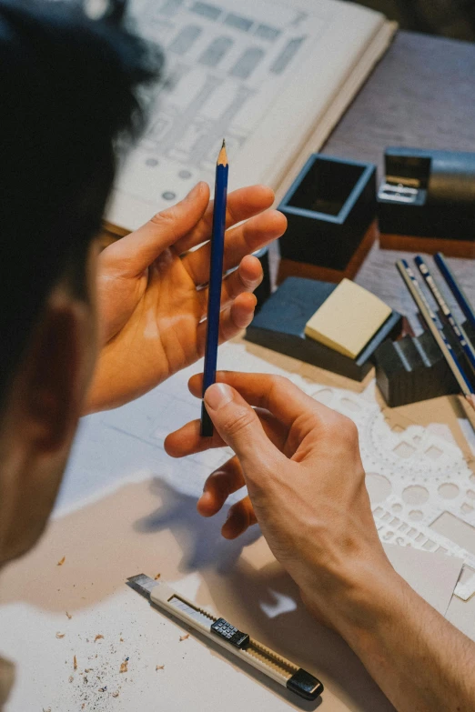 a man sitting at a table with a pencil in his hand, inspired by Kanō Naizen, pexels contest winner, arts and crafts movement, carved from sapphire stone, instagram post, product design, ross tan