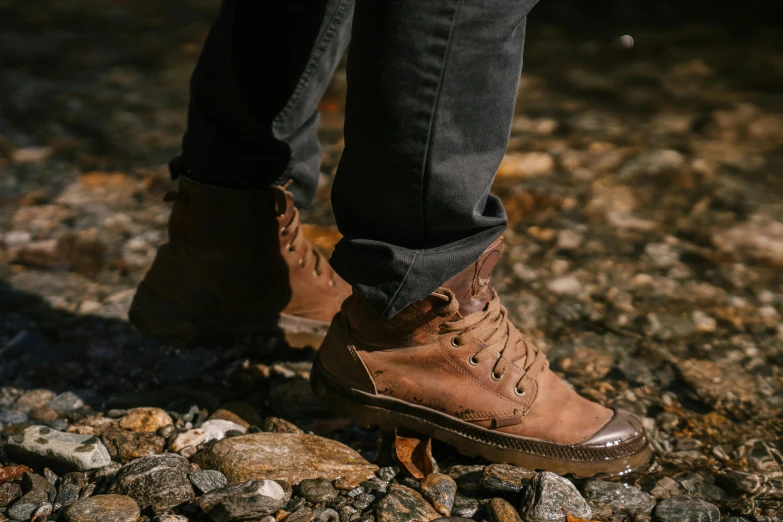 a person standing on top of a pile of rocks, gum rubber outsole, chocolate. rugged, ocher details, mid-shot of a hunky