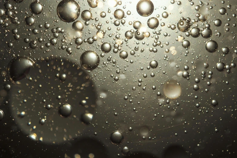 a close up of water bubbles on a surface, inspired by Otto Piene, unsplash, hyperrealism, glowing with silver light, lights on ceiling, dusty volumetric lighting, silver gold fractal details