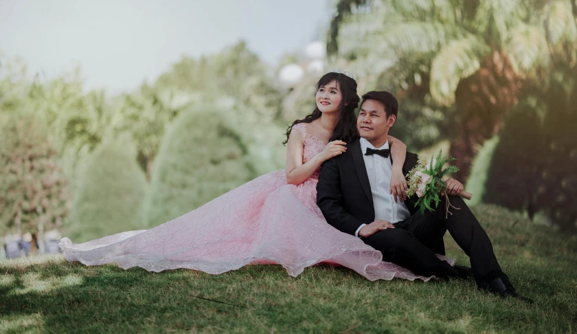 a man in a tuxedo sitting next to a woman in a pink dress, a picture, by Basuki Abdullah, sunny day time, premium quality, high quality upload, gown