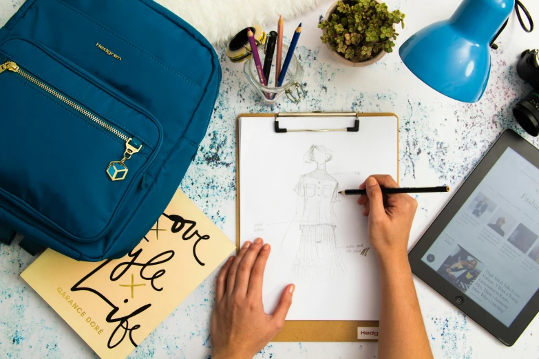 a person is drawing on a piece of paper, behance contest winner, outfit designs, the handbag is over a wood table, avatar image, blue print