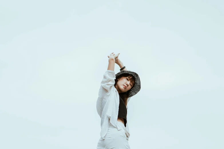 a woman standing on top of a sandy beach, pexels contest winner, minimalism, baggy clothing and hat, white background : 3, looking upwards, asian girl