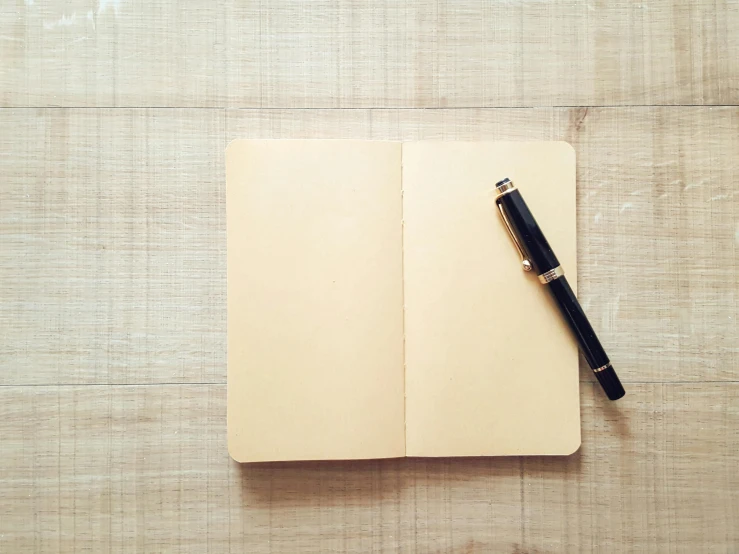 a pen sitting on top of an open notebook, pexels, minimalism, pale yellow wallpaper, square, wooden, background image