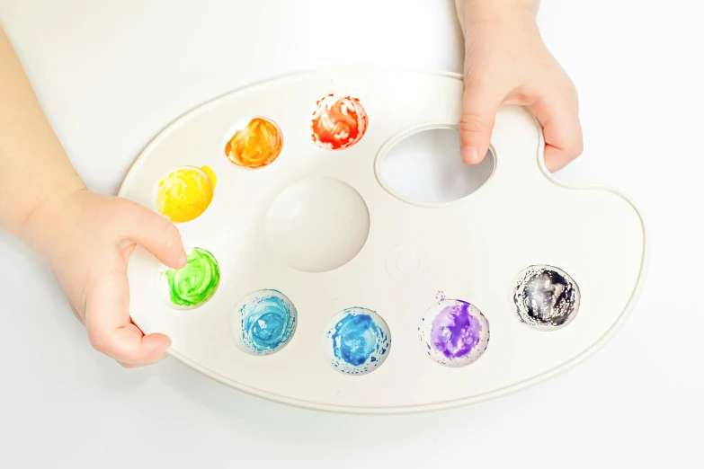 a close up of a person holding a paint palette, inspired by Damien Hirst, interactive art, on a white table, easy to use, milk puddles, multi colour