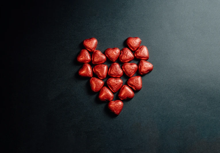 chocolate hearts in the shape of a heart on a black background, an album cover, pexels, hurufiyya, metallic red, snacks, wearing red, thumbnail