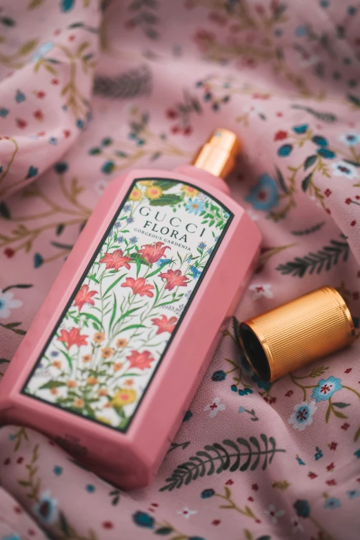 a bottle of perfume sitting on top of a bed, inspired by Eugène Grasset, soft blush, indonesia, made of wildflowers, gucci clothes