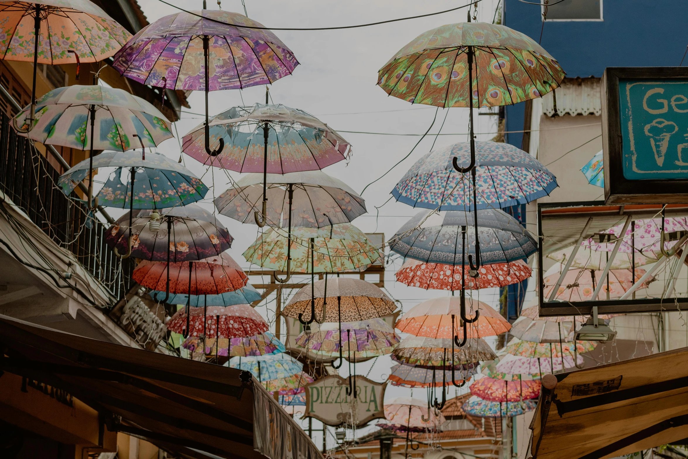 a bunch of umbrellas hanging from the side of a building, a colorized photo, trending on unsplash, street lanterns, slide show, paisley, anna nikonova