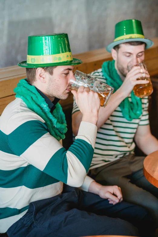 two men sitting at a table drinking beer, a photo, by Adam Marczyński, shutterstock, wearing green tophat, green flags, 🍸🍋, 2 5 6 x 2 5 6 pixels