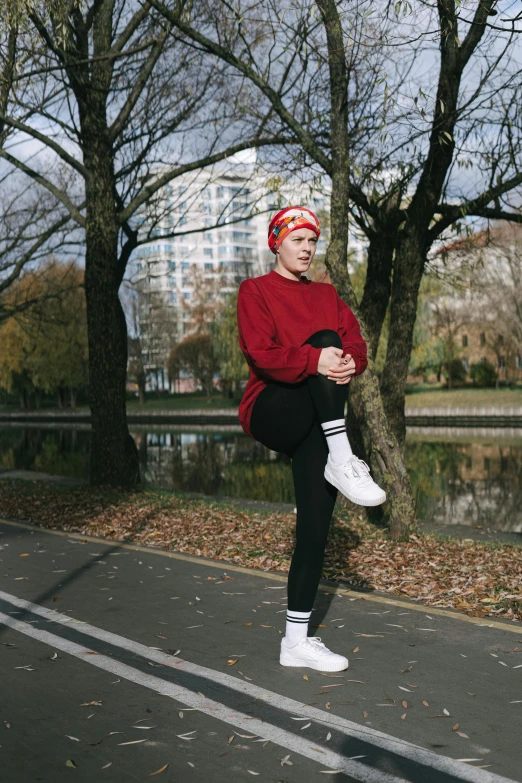 a man in a red sweater is doing a trick on a skateboard, an album cover, by Jacob Toorenvliet, unsplash, forest city streets behind her, an epic non - binary model, sitting at a pond, red headband