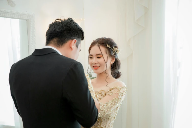 a man standing next to a woman in a wedding dress, pexels contest winner, cai xukun, delicate detailing golden stroke, on a white table, cheerful expression