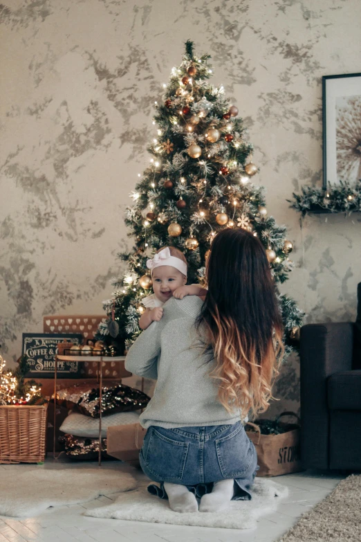 a woman holding a baby in front of a christmas tree, pexels contest winner, symbolism, lots of decoration and furniture, back towards camera, gif, profile image