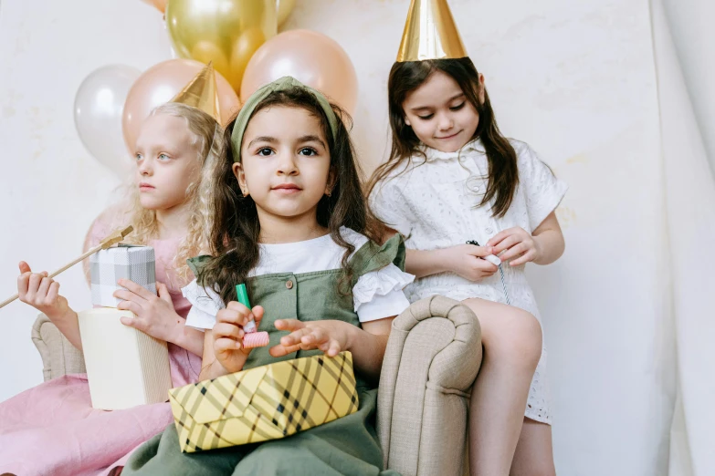 a group of little girls sitting next to each other, by Emma Andijewska, pexels, party balloons, holding a gold bag, olive skin color, thumbnail