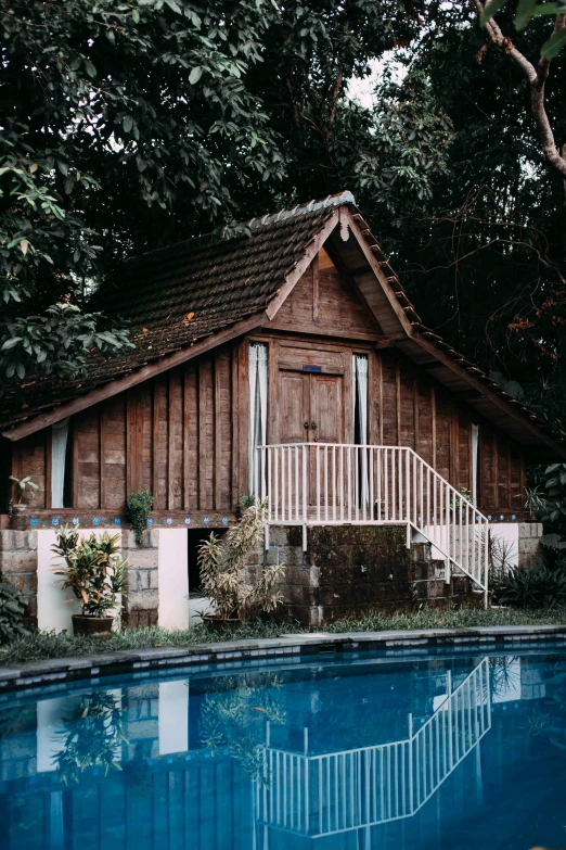 a house with a pool in front of it, unsplash, renaissance, stood outside a wooden cabin, jakarta, kerala village, 2 0 0 0's photo